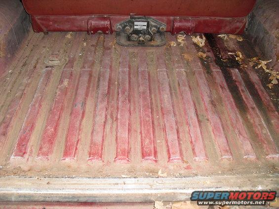 Red ribbed cargo floor with dirt and debris, and a fifth wheel hitch