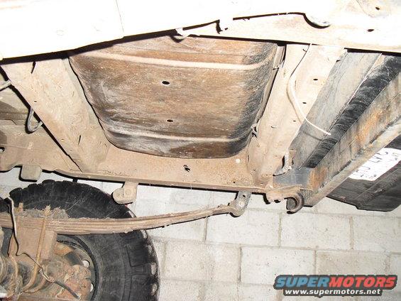 Underside view of vehicle showing fuel tank, leaf spring, and rear axle component