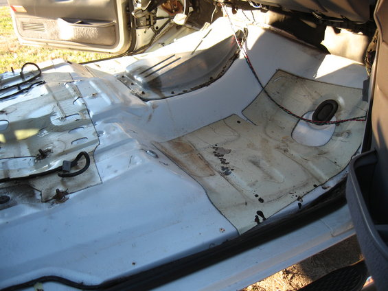 Interior floor of vehicle with carpet removed, showing metal and wiring