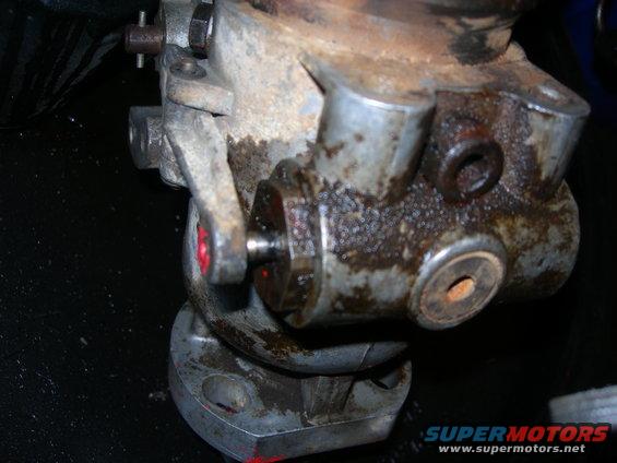 Close-up of a greasy, metallic automotive component with bolts and rust
