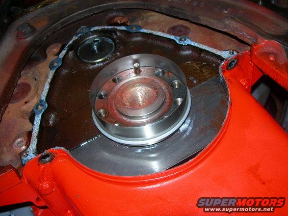 Close-up of a metal engine component with a gasket and bolts
