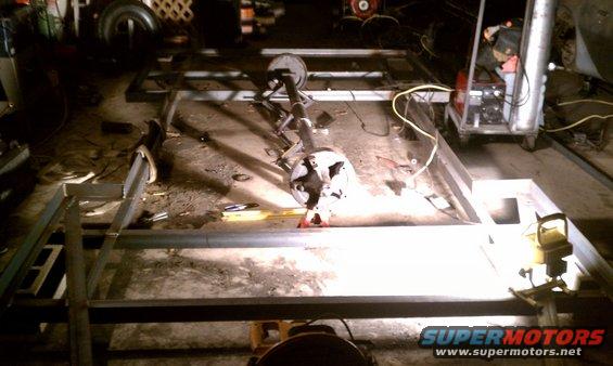 Trailer frame being constructed with metal tubing and an axle assembly on jack stands