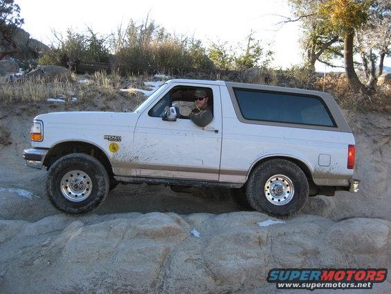 White 1996 Ford Bronco driving over rocks