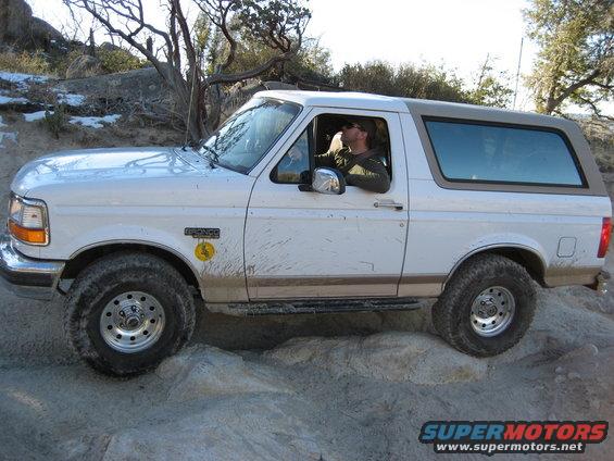 White 1996 Ford Bronco with tan top on rocky terrain, driver visible
