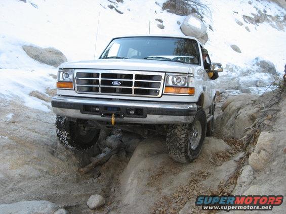 1996 Ford Bronco navigating a rocky off-road trail with snow in the background
