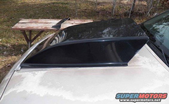 Black aftermarket rear window louvers resting on a car's trunk lid