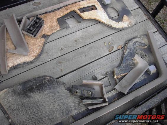 Disassembled car door panels with fabric and plastic components on a wooden surface