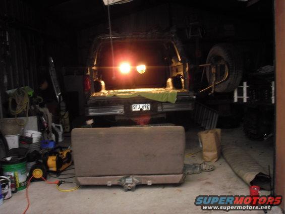 Rear view of a dark 1992 Ford Bronco with its tailgate open and brake lights illuminated