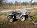 1993 Ford Bronco - An all-terrain vehicle sits in a grassy area with a fence and trees in the background.