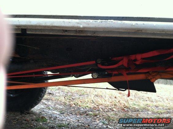 Underside of vehicle with red and orange straps securing it