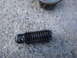 2003 Ford Taurus - A close-up view of a stripped bolt and a portion of a motor mount resting on a concrete surface.
