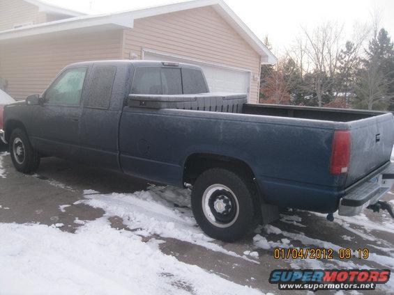 Dark blue pickup truck with a toolbox in the bed, parked in snow