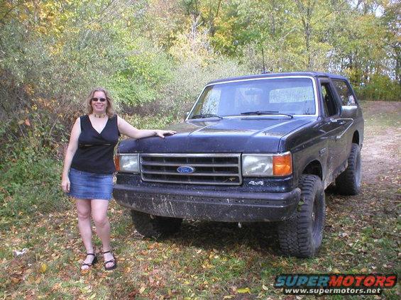 Dark blue 1989 Ford Bronco with a woman standing beside it