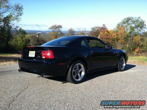 Black 2002 Ford Mustang coupe parked on asphalt, rear 3/4 view