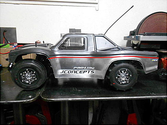 Silver RC truck with red stripe and JCONCEPTS logo. Has an antenna sticking up