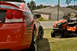 2009 Dodge Charger - A red 2009 Dodge Charger is parked on the grass next to a riding mower in front of a house.