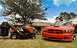 2009 Dodge Charger - An orange 2009 Dodge Charger SRT is parked on a lawn next to a riding mower under a partly cloudy sky.