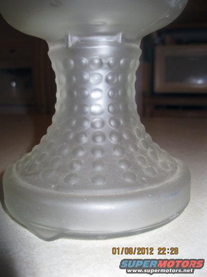 Frosted glass object with raised circular pattern, on a surface with a timestamp and website