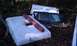 1979 Ford Bronco - Vehicle parts including a camper shell and tailgate are piled up outdoors.