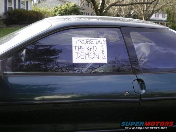 Dark green coupe side view, sign on window reads 'PROBETALK THE RED DEMON 1 8 12'