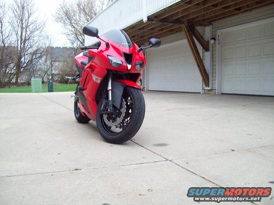 Red sport motorcycle parked on concrete in front of a garage