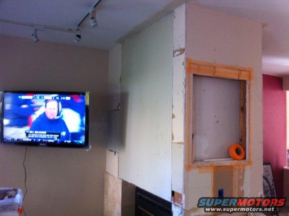 Interior scene with TV on wall and fireplace under renovation