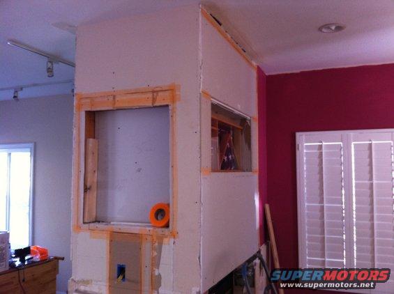 Interior wall under construction with exposed framing, drywall, and an orange roll of tape