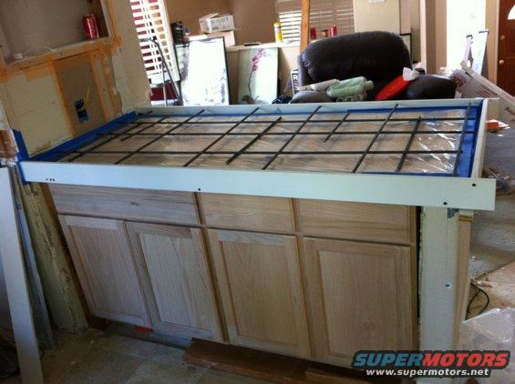 Kitchen island under construction with rebar grid on top of cabinets