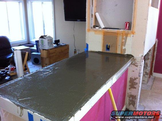 Countertop form with wet concrete being poured, construction materials visible