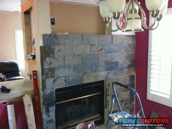 Fireplace with slate tile surround, unfinished mantle, and construction materials
