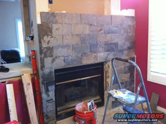 Fireplace with slate tile installation in progress, tools and materials nearby