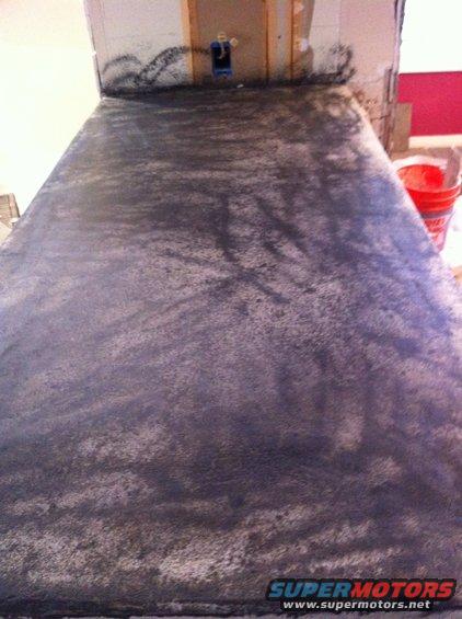 Countertop surface with dark speckled finish, unfinished wall behind it with electrical box