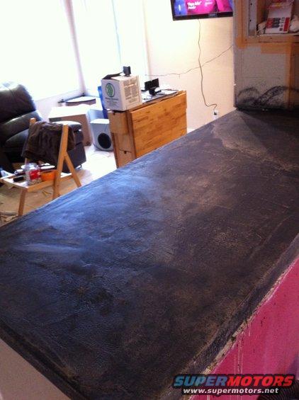 countertop with dark finish, living room in background with TV and furniture