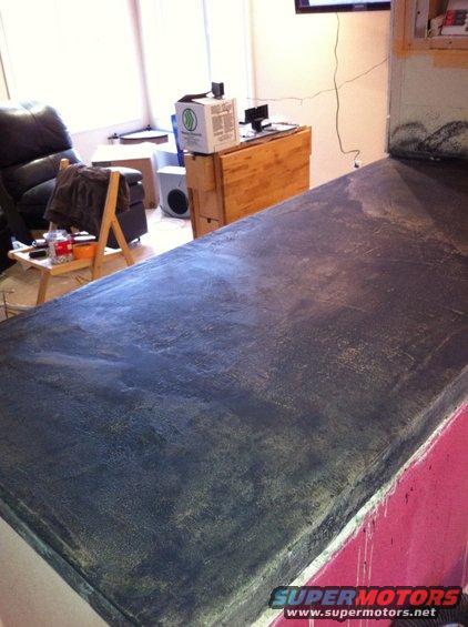 Dark grey countertop with textured finish, red base, and a Supermotors logo at the bottom right