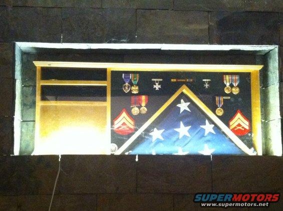Shadow box containing a folded American flag, military medals, and rank insignia