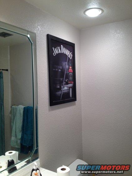 Bathroom with Jack Daniel's poster, mirror, towels, and toilet paper