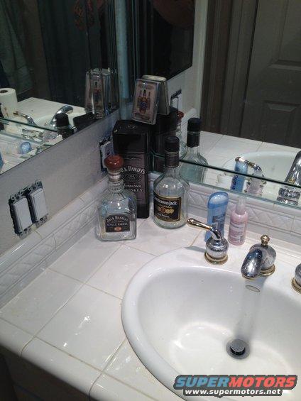 Bathroom counter with Jack Daniels bottles, toiletries, and a sink