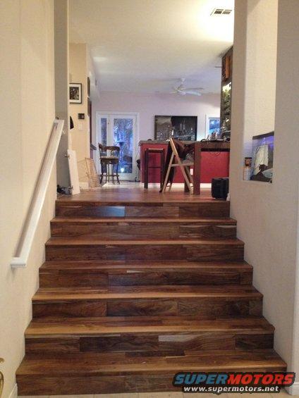 Wooden staircase leading to an open living area with a red island and chairs