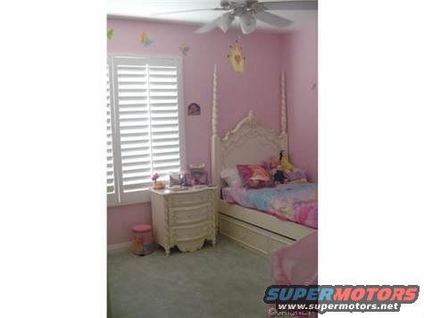 Pink bedroom with a four-poster bed and white shutters
