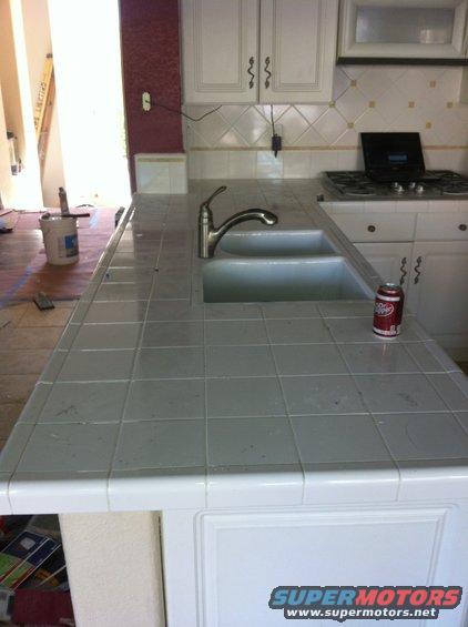 Kitchen counter with a double sink, faucet, and a can of Dr. Pepper. A stove is visible in the background