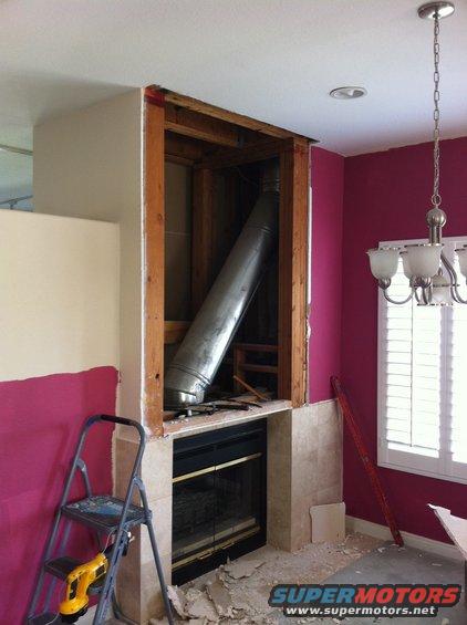 Fireplace under renovation with exposed ductwork and a ladder