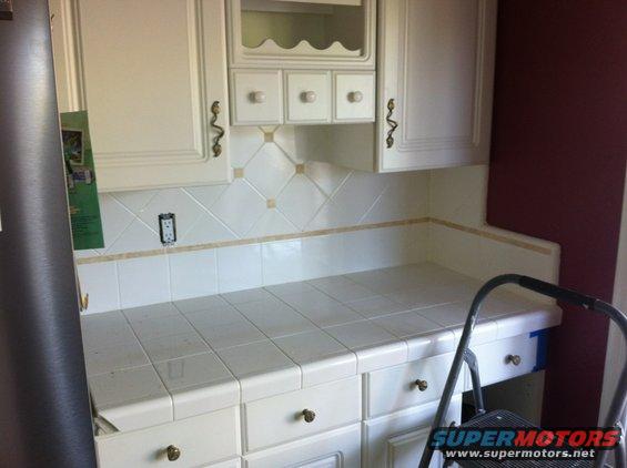 Kitchen counter with white tiled backsplash and cabinets. A step ladder is partially visible on the right