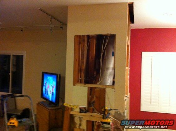 Interior scene with exposed studs, a television, and construction tools
