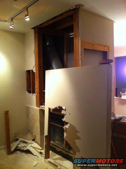 Interior of a room with exposed framing, drywall, and a fireplace opening during renovation