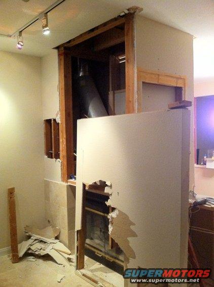 Fireplace renovation in progress with exposed framing and drywall
