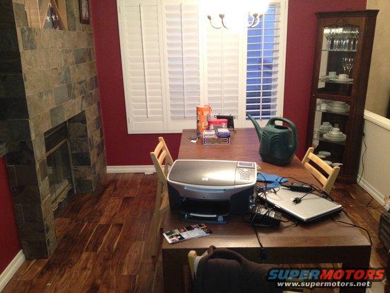 Dining room table with HP printer, laptop, watering can, and boxes