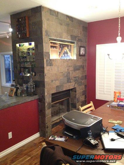 Interior scene with a stone fireplace, bar area, and dining table with a printer