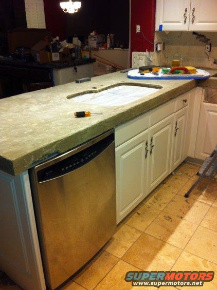 Kitchen counter with sink cutout and dishwasher installed, tools on counter