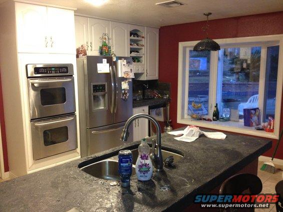 Kitchen scene with stainless steel appliances, granite countertop, and a bay window