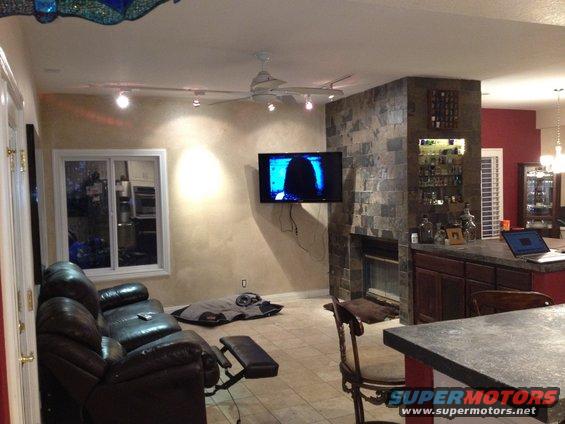 Living room with leather sofa, fireplace, bar, and television